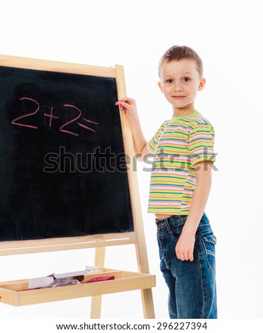 Preschooler child standing nearby  chalkboard with easy math example