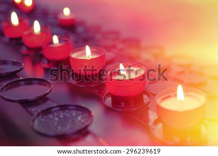 Small firing candles in catholic church on dark background. Filtered photo with effects Royalty-Free Stock Photo #296239619