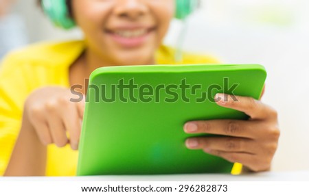 people, technology and leisure concept - close up of happy african american young woman lying with tablet pc computer and headphones listening to music at home