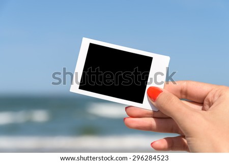 Girl Hand Holding Blank Instant Photo Card On Beach In Summer