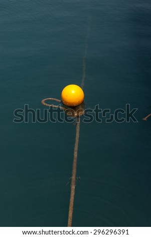 Single yellow buoy on calm blue sea water surface