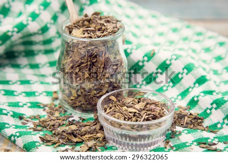 dry green tea in glass containers with spoon in studio