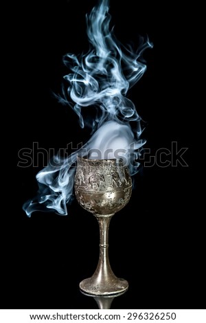 Wine goblet with smoke on black background