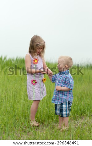 Picture of the girl and boy is a field playing with insects