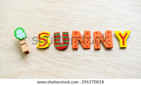 Weather symbol on wooden clothes peg and colourful text. Concept of climate weather. Slightly de-focused and close up shot. Copy space.