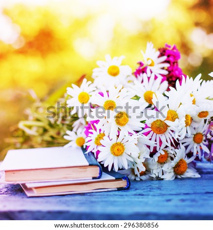 Vintage books with bouquet of daisy flowers/ nostalgic summer background 