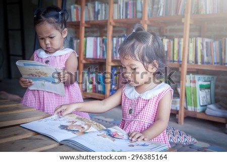 cute little girls reading books in library,vintage filter