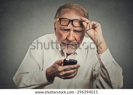 Closeup portrait headshot elderly man with glasses having trouble seeing cell phone has vision problems. Bad text message. Negative human emotion facial expression perception. Confusing technology Royalty-Free Stock Photo #296394011