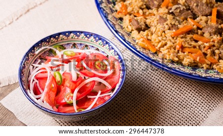 Pilaf and achichuk salad in handmade plate on wooden background. Horizontal, wide screen