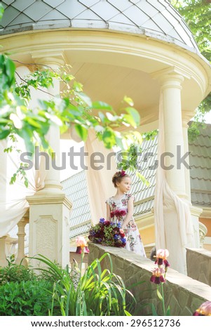 Small girl in colorful dress and flowers outdoor in the park. Facial expression.
