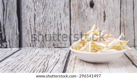 Bean sprout in white bowl over weathered wooden background