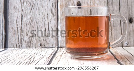 A mug of tea over weathered wooden background