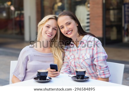 Happy women friends smiling at camera outside at a cafe