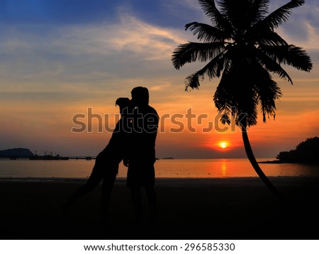 silhouette of romantic lovers over Coconut trees and beautiful sunset. Romantic lovers Concept