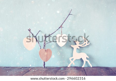 hanging wooden hearts over and wooden rain deer decoration over wooden background. retro filtered image
