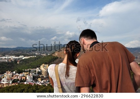 Young couple taking photo of Malaga cityscape from Alcazaba Castle.