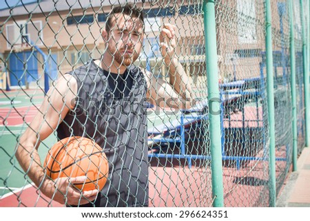 young man with a basketball behind a fence