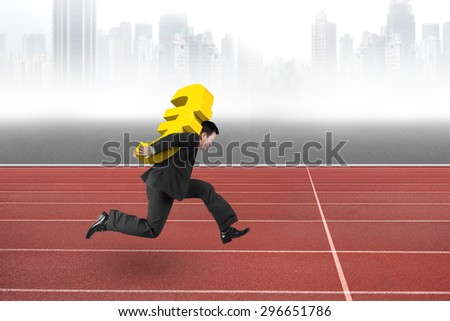 Businessman carrying 3D golden euro sign running on red track, with gray city skyline background.