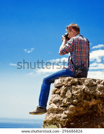 Photographer sits on top of a mountain and taking pictures