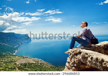 tourist sits on top of the mountain and enjoy the view of the sea