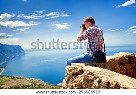 Photographer sits on top of a mountain and taking pictures