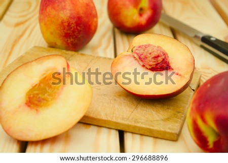 Fresh, vegetarian, juicy red and yellow sliced and whole nectarines on a cutting board with the knife in the background