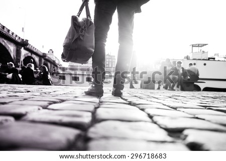 Young stylish man with his bag is standing in front of river and looking in the city. Detail of his shoes and his bag. Moment of the arriving the city. Black and white photography.