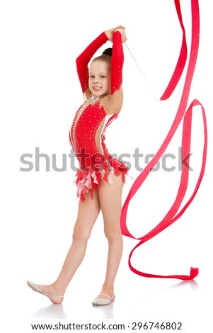 Very slender and beautiful young girl in a red bathing suits embroidered sequined perform exercises with the tape , the girl is engaged in gymnastics , she prepares to compete-Isolated on white
