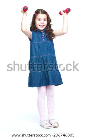 Smiling dark-haired girl in a short denim dress and white stockings is holding in his outstretched hands dumbbell that the girl is engaged in morning exercises-Isolated on white