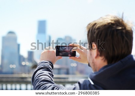Middle age tourist taking mobile photo of skyscrapers using his smart phone