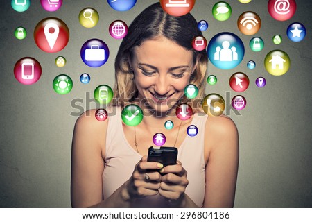 communication technology mobile high tech concept. Closeup happy young woman using texting on smartphone with social media application symbols icons flying out of screen isolated on grey background.