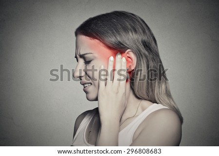 Tinnitus. Closeup up side profile sick female having ear pain touching her painful head temple isolated on gray wall background Royalty-Free Stock Photo #296808683