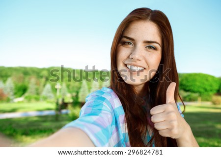 Beautiful girl taking selfie in the park
