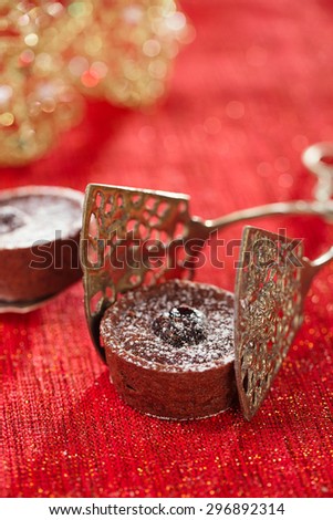 Chocolate Cherry Mini Tartlets in vintage tongs  with festive golden red style, shallow dof