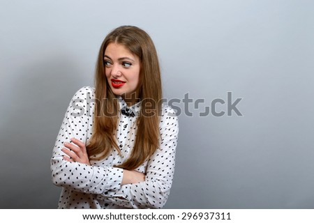Girl with condemning glance, crossed hands on grey background