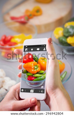 Hand holding smartphone against close up of pimentos