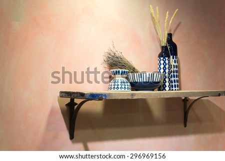 Rustic Country Shelf with Blue and White Ceramic Bowls and Vases on Traditional Stucco Wall with Copy Space