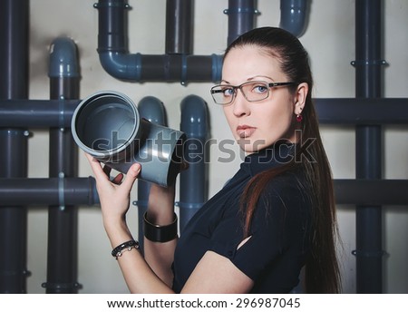 Businesswoman holding PVC pipe connector on a pipes background