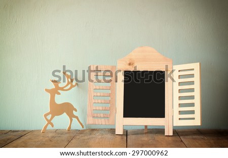 abstract filtered photo of decorative chalkboard frame and wooden deer over wooden table. ready for text or mockup
