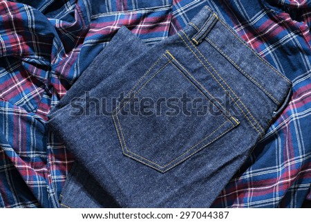 Blue Jeans Denim, 100% Cotton Un sanforized Denim Red Selvage Jeans on Plaid Shirt background, selective focus (detailed close-up shot) Royalty-Free Stock Photo #297044387