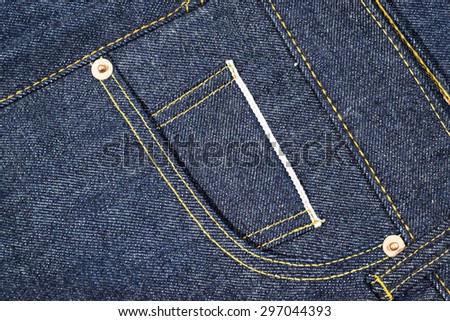 Blue Jeans Denim, 100% Cotton Un sanforized Denim Red Selvage Jeans on Plaid Shirt background, selective focus (detailed close-up shot) Royalty-Free Stock Photo #297044393