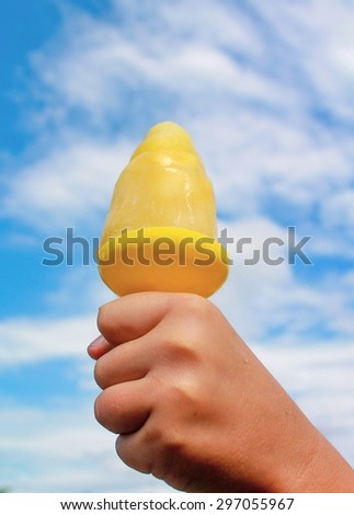 Child hand holding a homemade ice lolly against blue sky