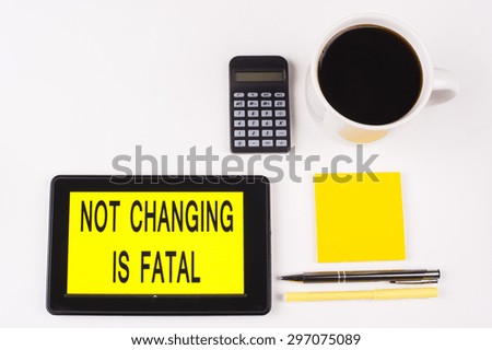 Business Term / Business Phrase on Tablet PC with a cup of coffee, Pens, Calculator, and yellow note pad on a White Background - Black Word(s) on a yellow background - Not Changing Is Fatal