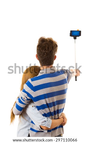 Couple with selfie stick posing for mobile back facing camera.