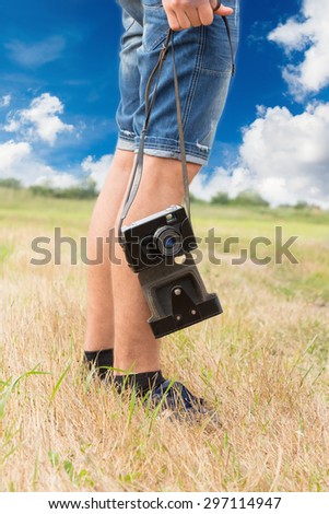 Vertical image of tourist legs with a camera.