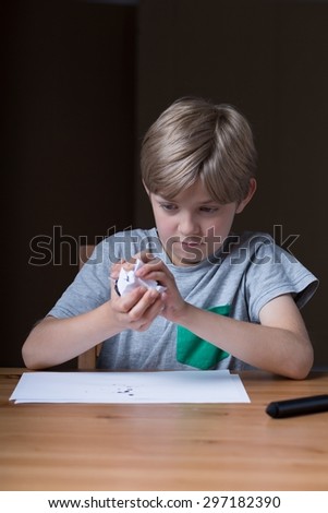 Photo of displeased small kid crumpling sheet of paper