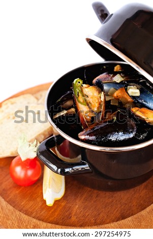 Copper pot of gourmet mussels served on a wood plate garnished with fresh herbs and lemon for a tasty seafood meal