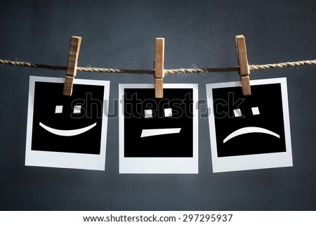 Happy, sad and neutral emoticons on instant print transfer photographs hanging on a clothesline
