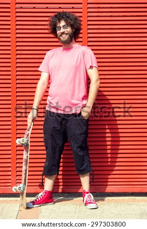 Man with skateboard on red background