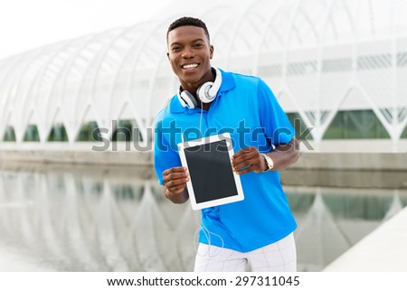 Black, African American college student wearing headphones and showing a digital tablet computer
